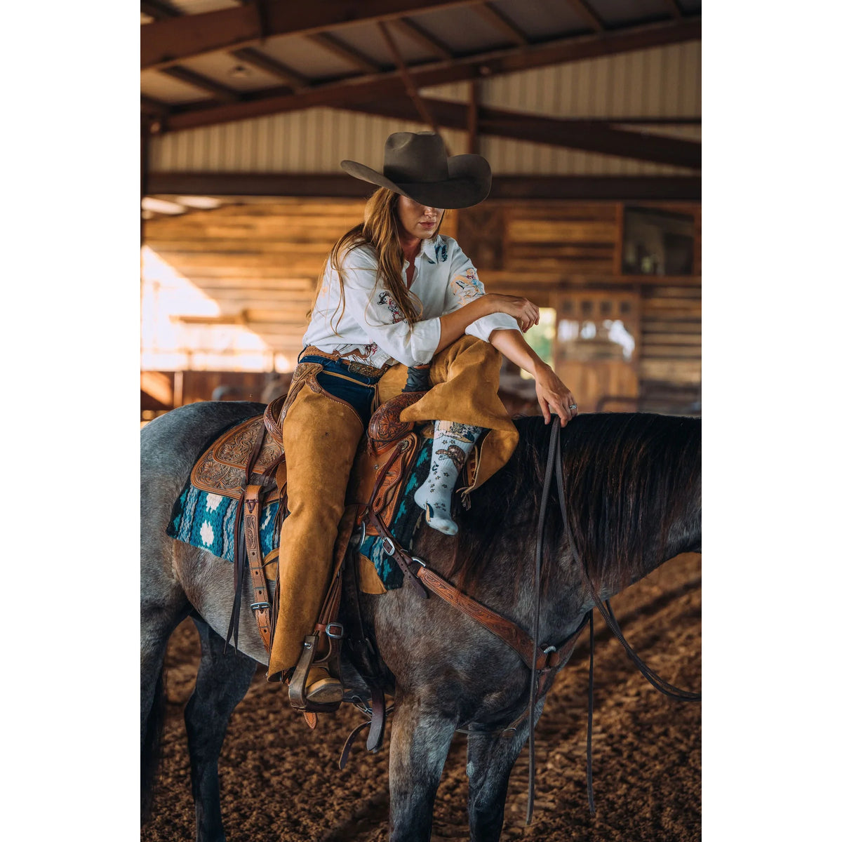 A Woman on a horse wearing Lucky Chuck Cosmic Cowgirl performance boot socks in light blue