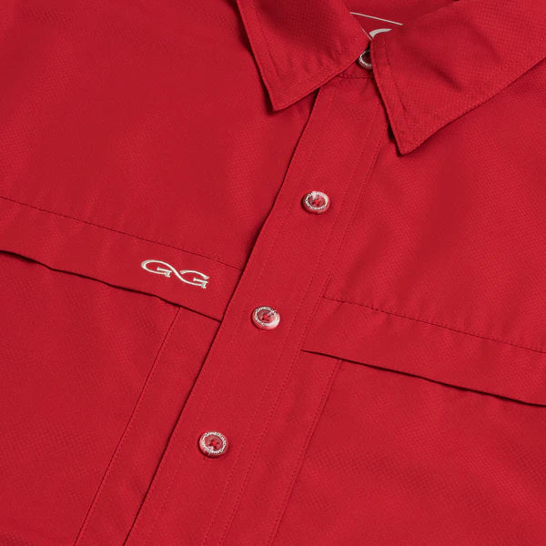 Close-up of a red collared button-up shirt with a chest pocket and silver-tone buttons, featuring a small white embroidered logo on the pocket.