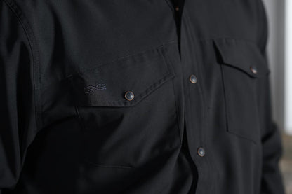 Close-up of a black button-front shirt with chest pockets and metallic snap buttons, worn by a person.