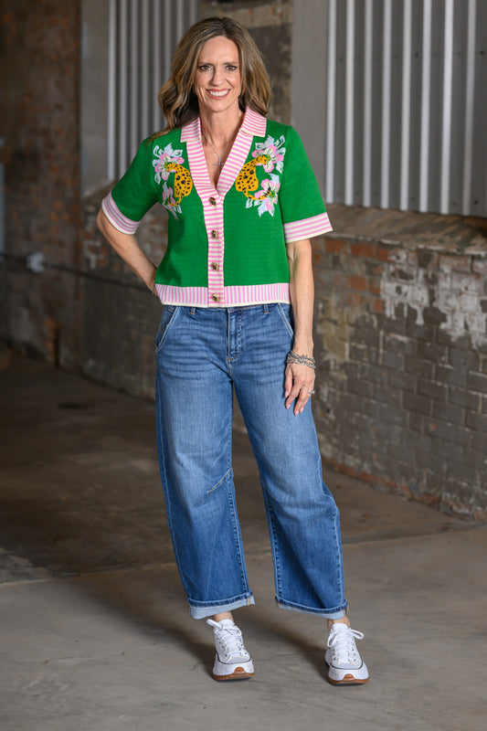 Jennifer Smith wearing a green short-sleeve cardigan with yellow leopard motifs, floral accents and pink striped trim by THML