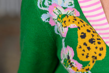 Close-up of yellow leopard and pink floral knit design beside the striped placket on a green cardigan