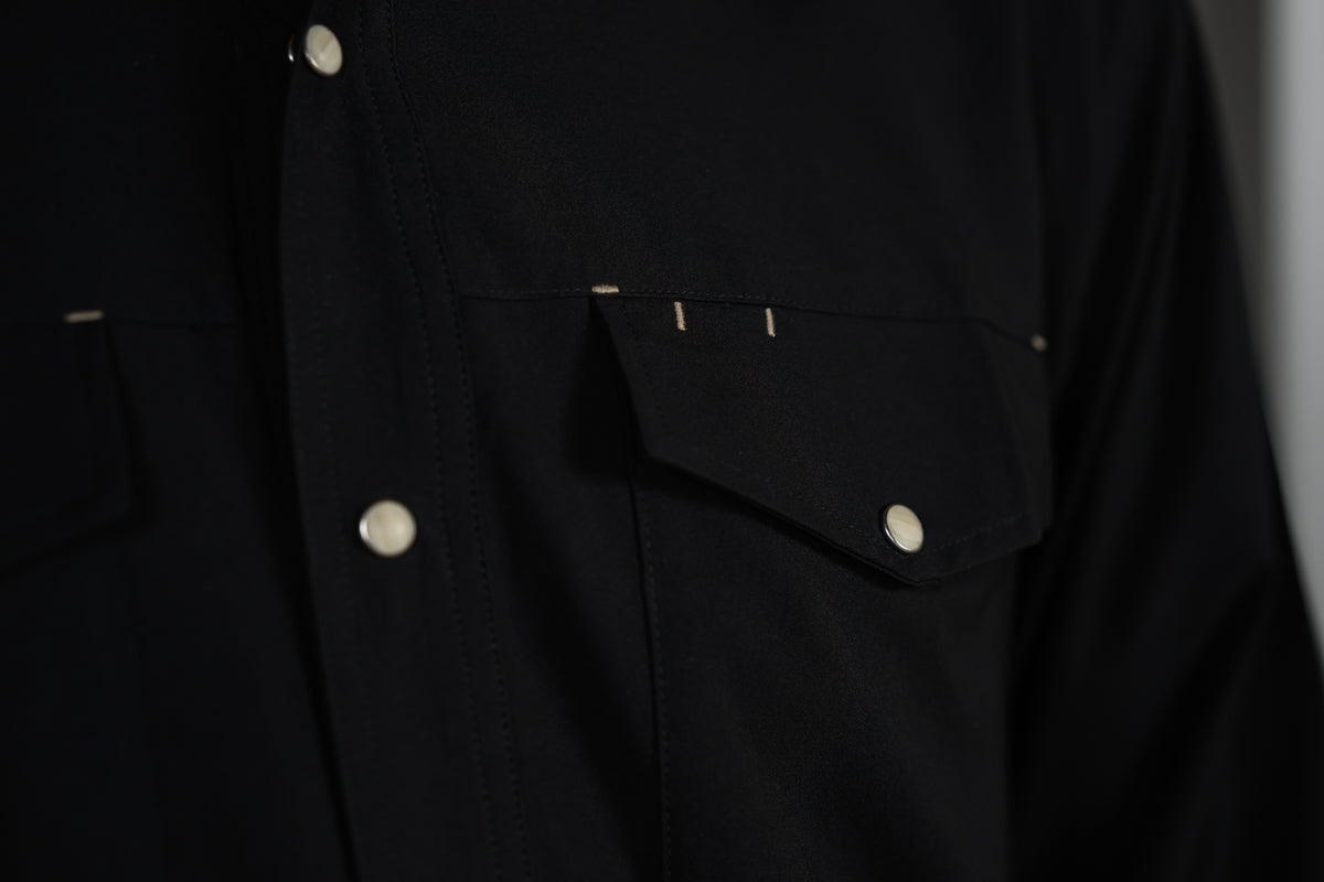 Detail of the black GameGuard Stockyard Shirt chest pocket with snap closure and contrast accent stitching