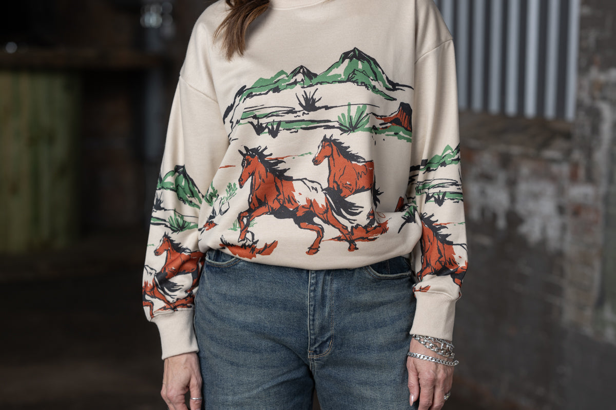 close up of Jennifer Smtih of STS Ranch/1930 Remnant modeling a beige sweatshirt with a running horse graphic across the front, back and sleeves.