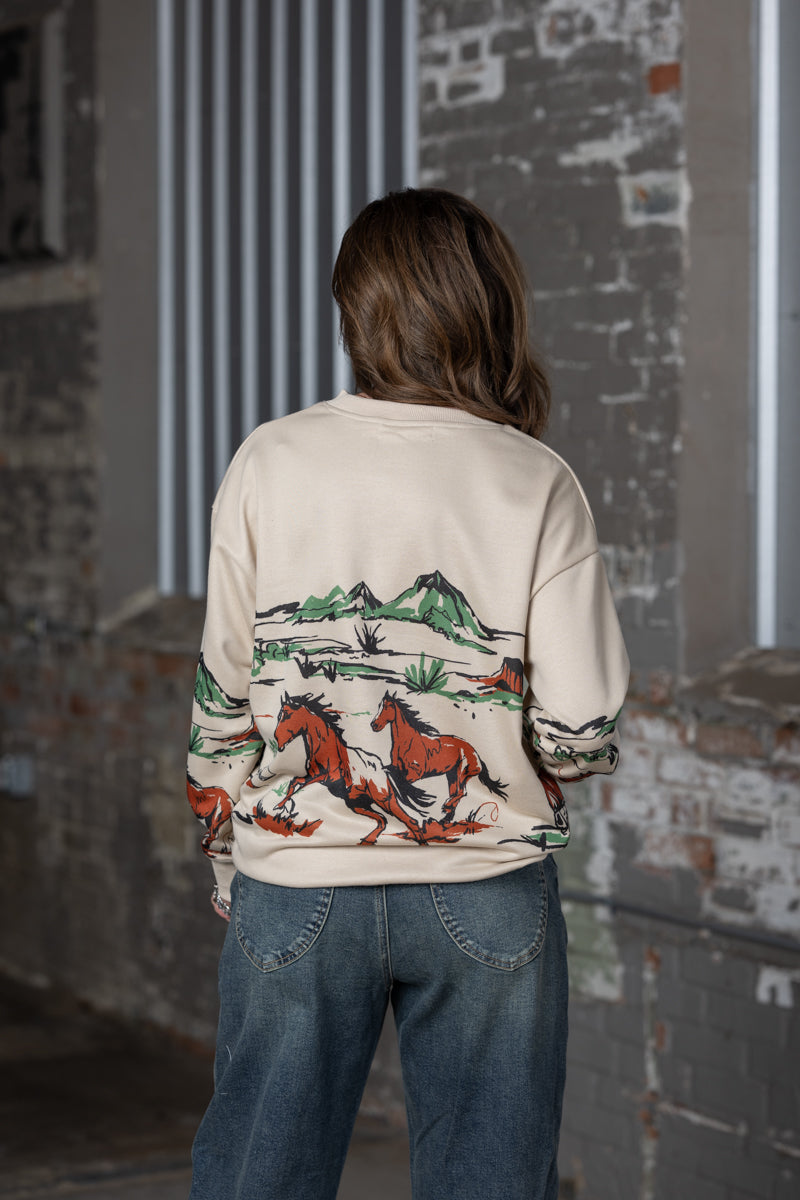 back view of Jennifer Smtih of STS Ranch/1930 Remnant modeling a beige sweatshirt with a running horse graphic across the front, back and sleeves.