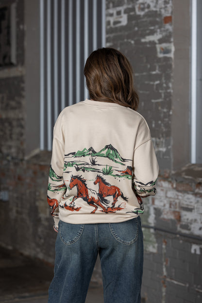back view of Jennifer Smtih of STS Ranch/1930 Remnant modeling a beige sweatshirt with a running horse graphic across the front, back and sleeves.