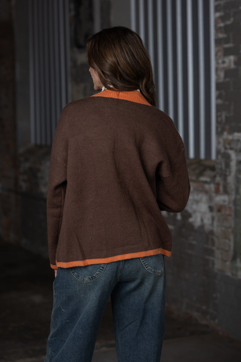 back view of Jennifer Smtih of STS Ranch/1930 Remnant modeling a brown & orange cardigan sweater with a horses detail on front