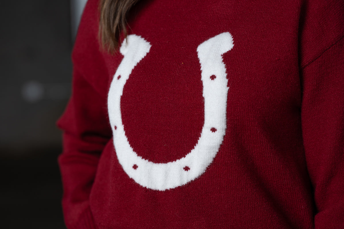 Close up Jennifer Smtih of STS Ranch/1930 Remnant modeling a maroon sweater with a horseshoe detail on front