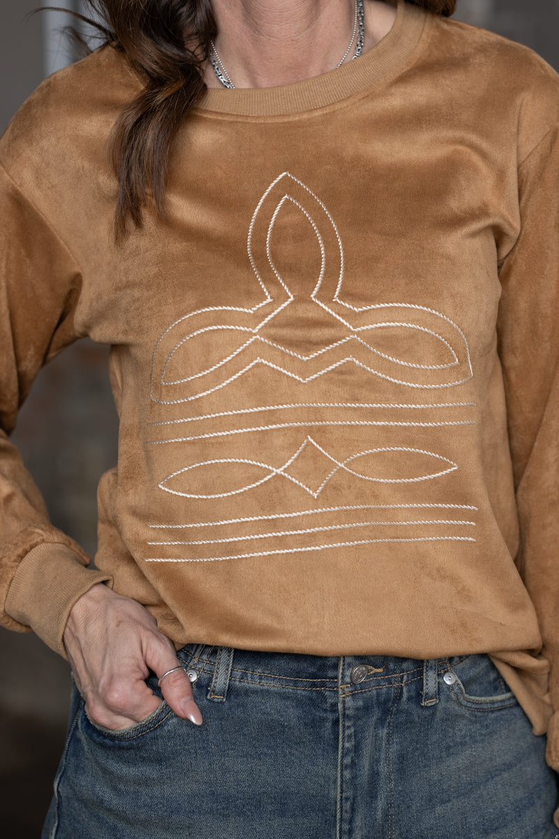 close up of Jennifer Smith of STS Ranch/1930 Remnant modeling a tan boot stitched shirt on a metal background