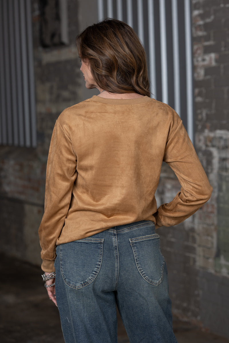 back view Jennifer Smith of STS Ranch/1930 Remnant modeling a tan boot stitched shirt on a metal background