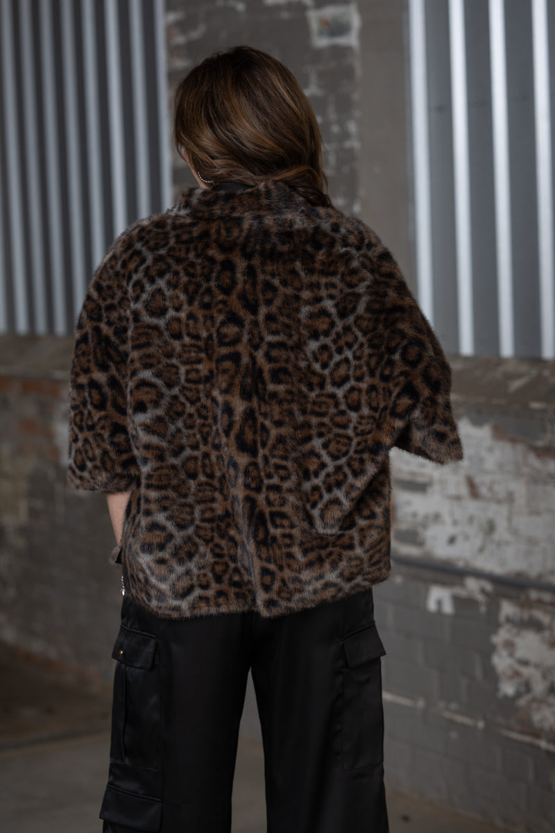 Jennifer Smith of 1930 Remnant/STS Ranch modeling the Ivy Jane Leopard Faux Fur Capelet Jacket over a black satin pantsuit back view 