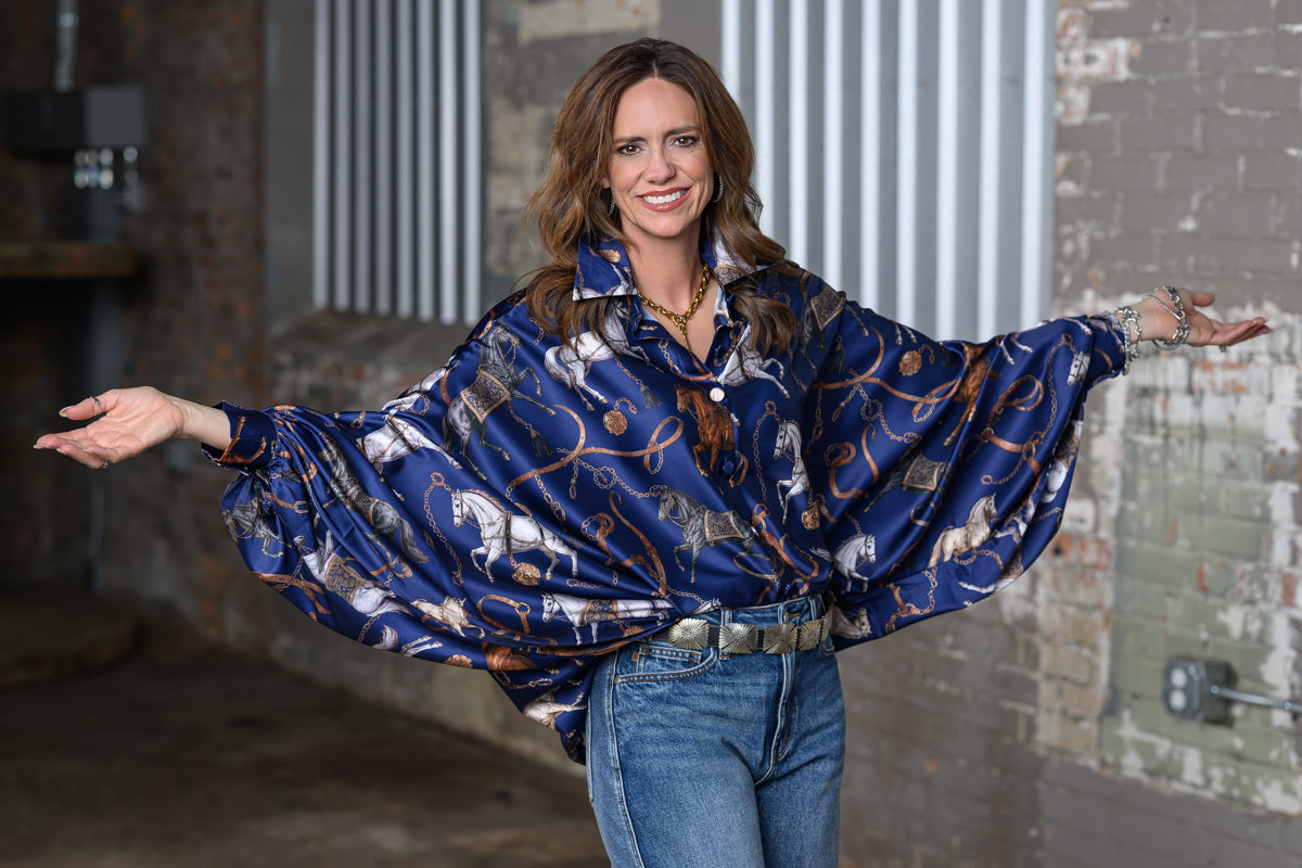 Jennifer Smith of STS Ranch/1930 Remnant wearing the Beulah Style Equestrian top in navy with arms out, featuring the dolman sleeves. 