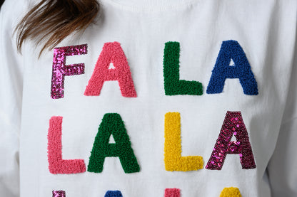 A close-up of a white crewneck sweater featuring colorful, textured sequin letters spelling out 'FA LA LA LA' 