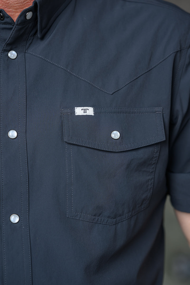 Close-up of a dark navy western-style short-sleeve button-up shirt with a chest pocket and a small white 'FF' logo patch.