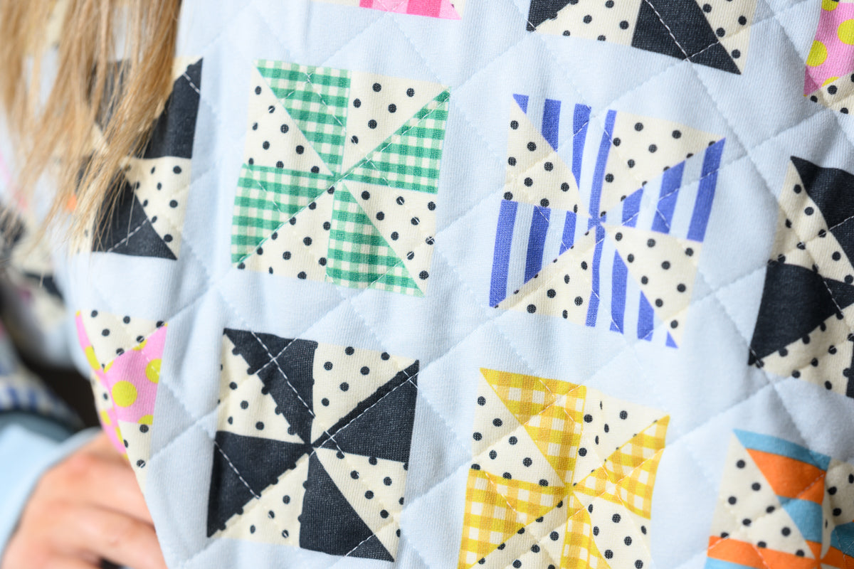 close of pf pattern on the Poppy & Pine Quilted Kaleidoscope Sweatshirt on a model with matching shorts