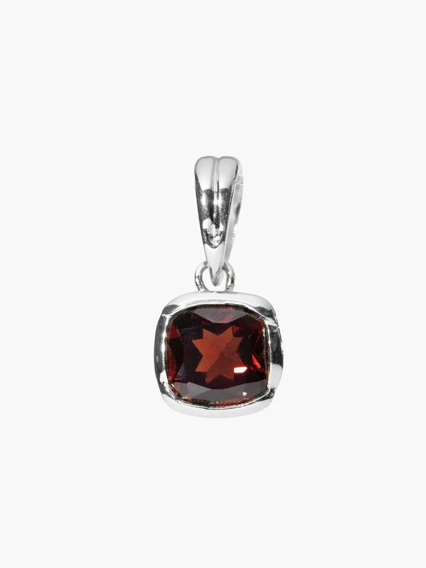 A silver pendant featuring a cushion-cut dark red garnet gemstone in a polished bezel setting, shown against a plain light gray background.