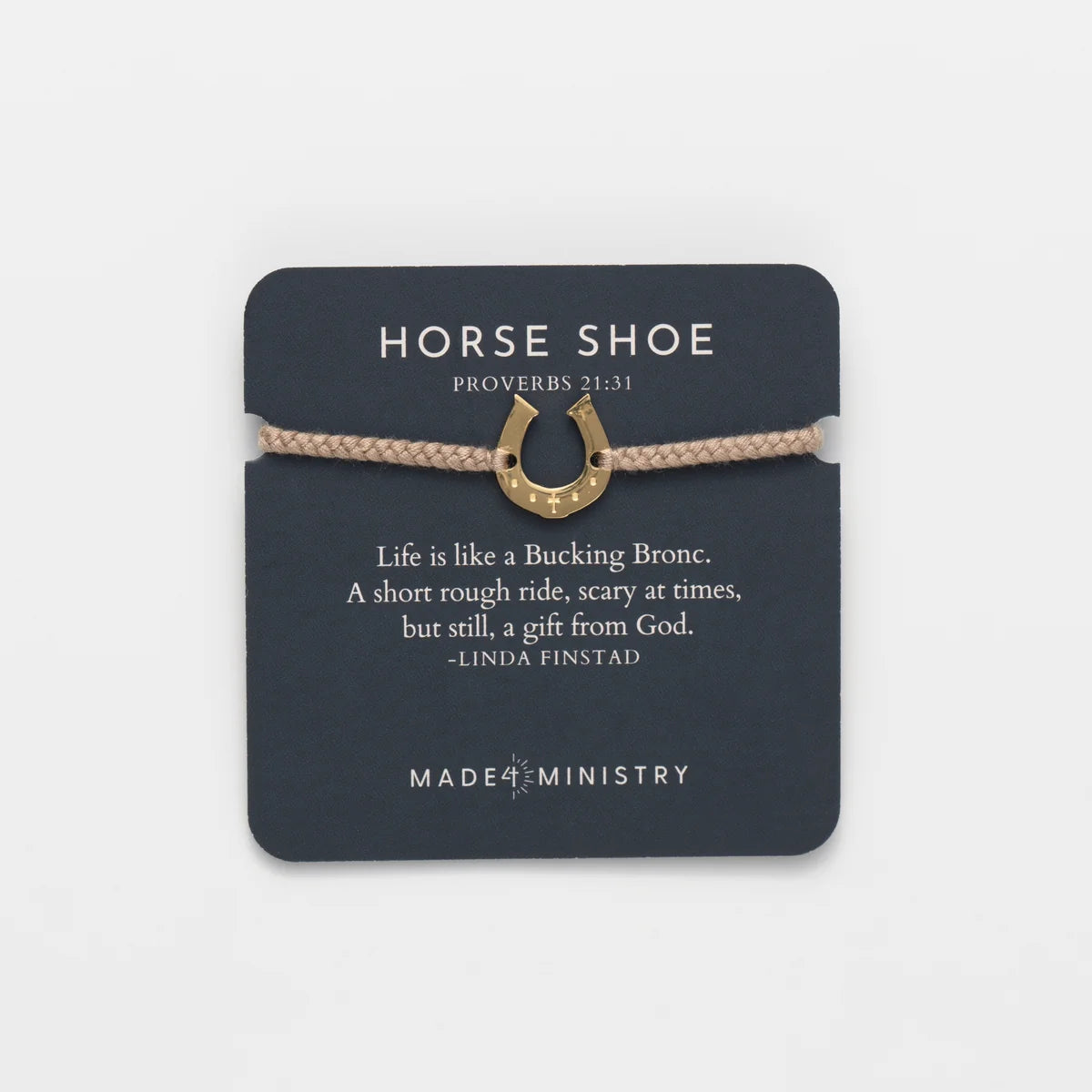 A horse shoe charm bracelet with a gold-colored metal horseshoe pendant and a beige braided cord, presented on a dark gray card that features a Bible verse and the brand name Made Ministry.