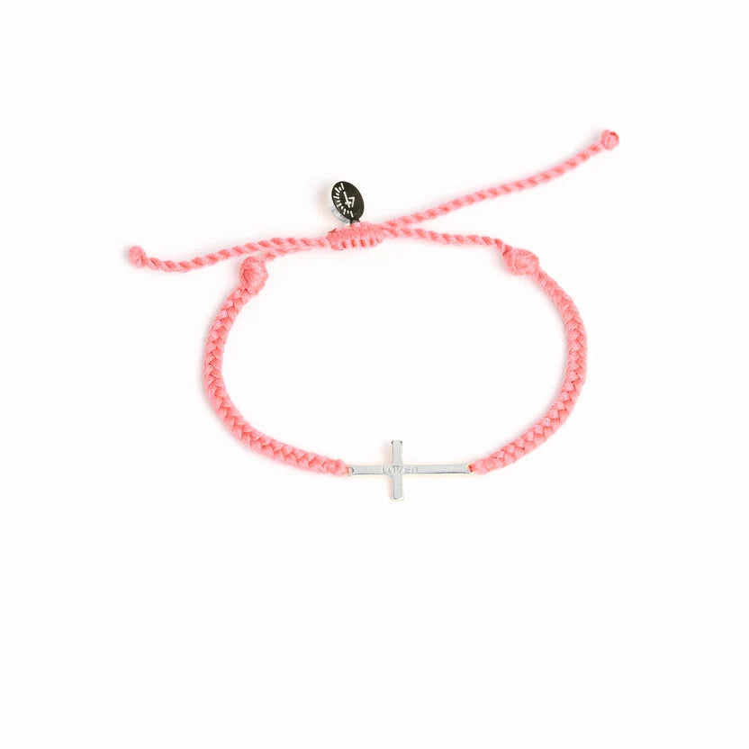 Pink bracelet with a white cross charm on a white background
