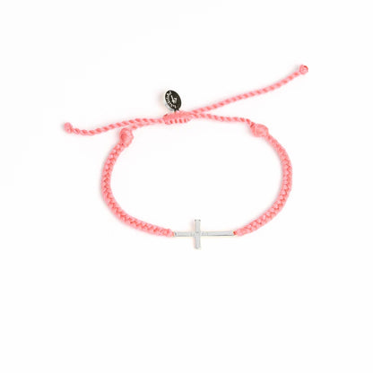 Pink bracelet with a white cross charm on a white background