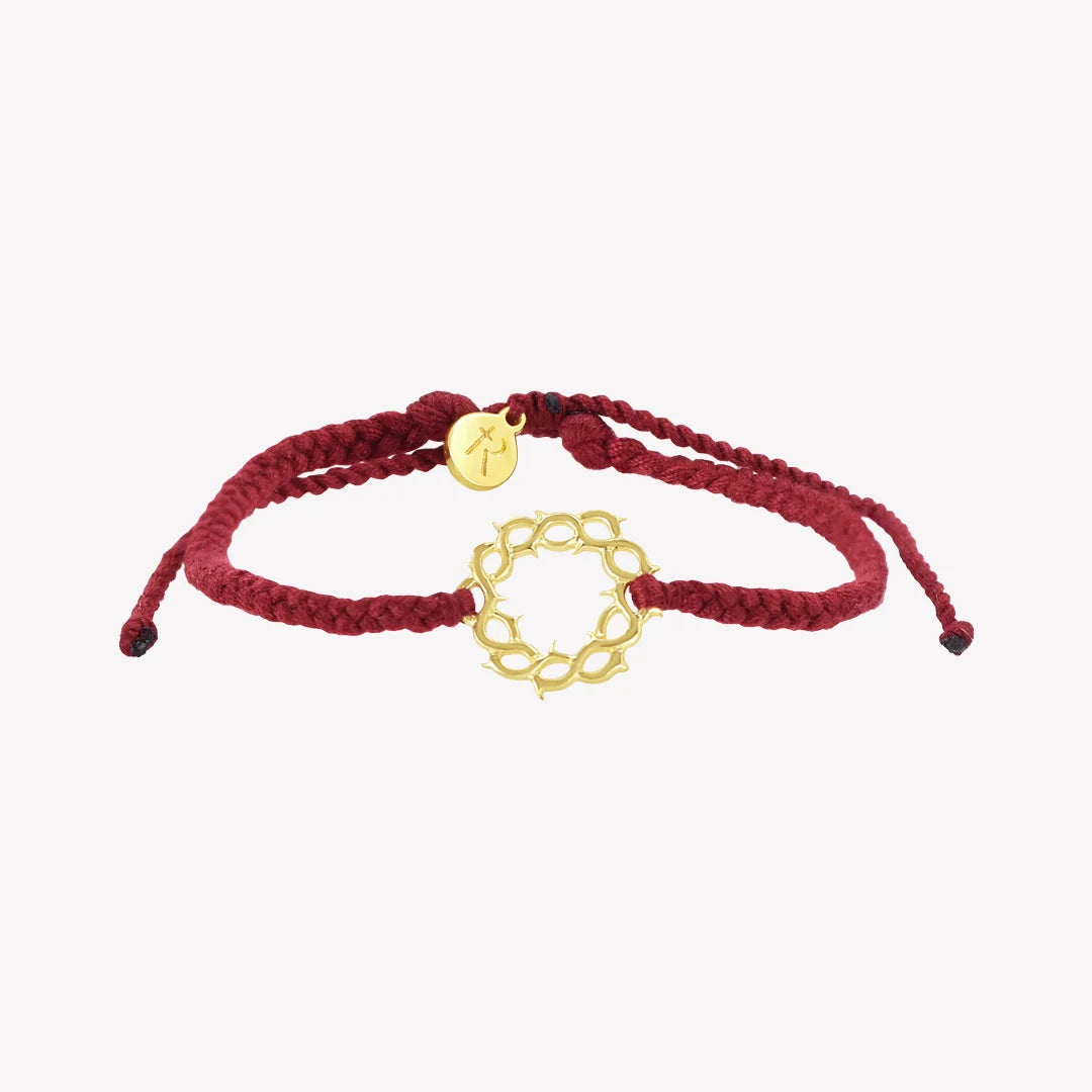 A red braided cord bracelet with a gold circular link charm and a small round gold disc charm, displayed on a light gray background.