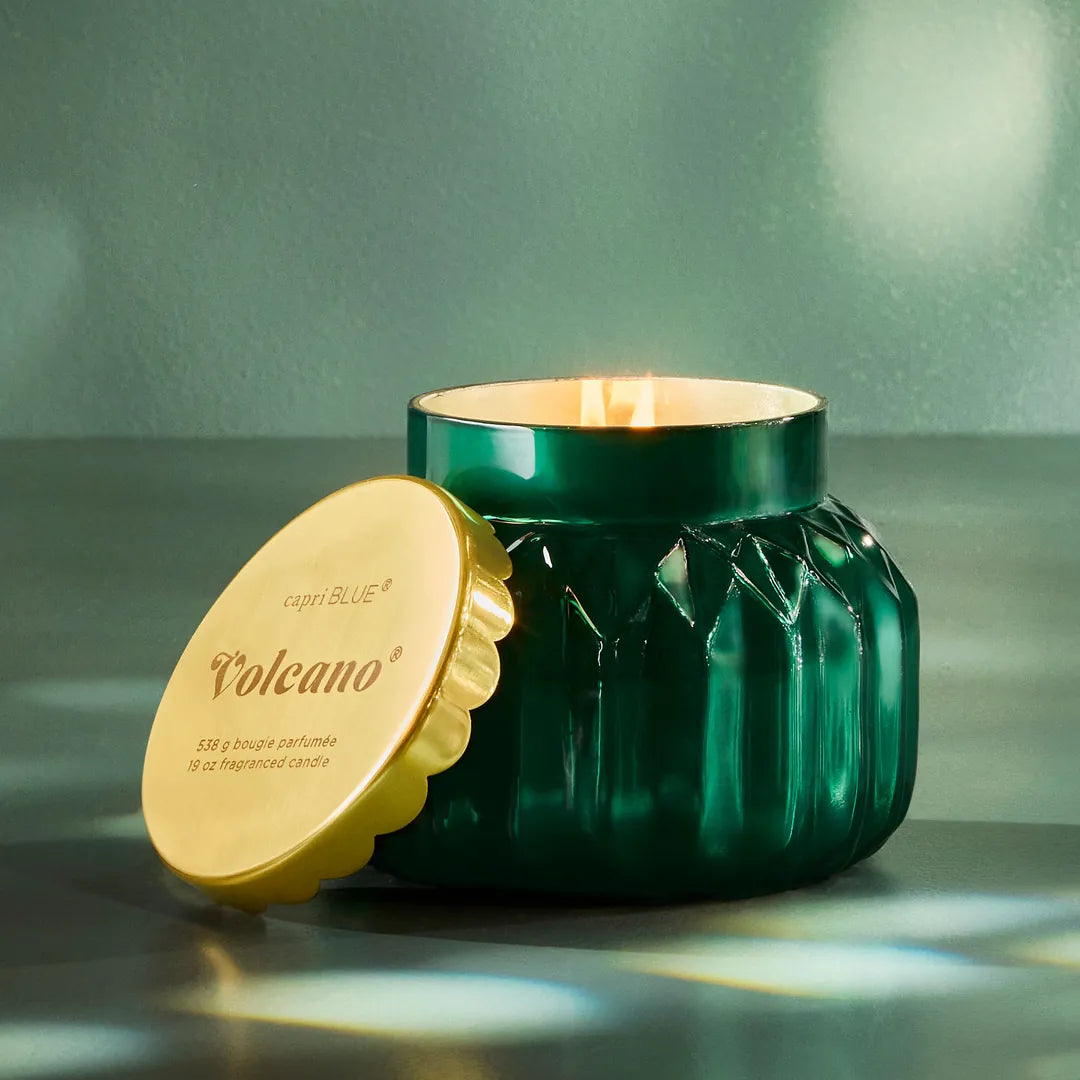 Green candle with gold lid on a reflective surface