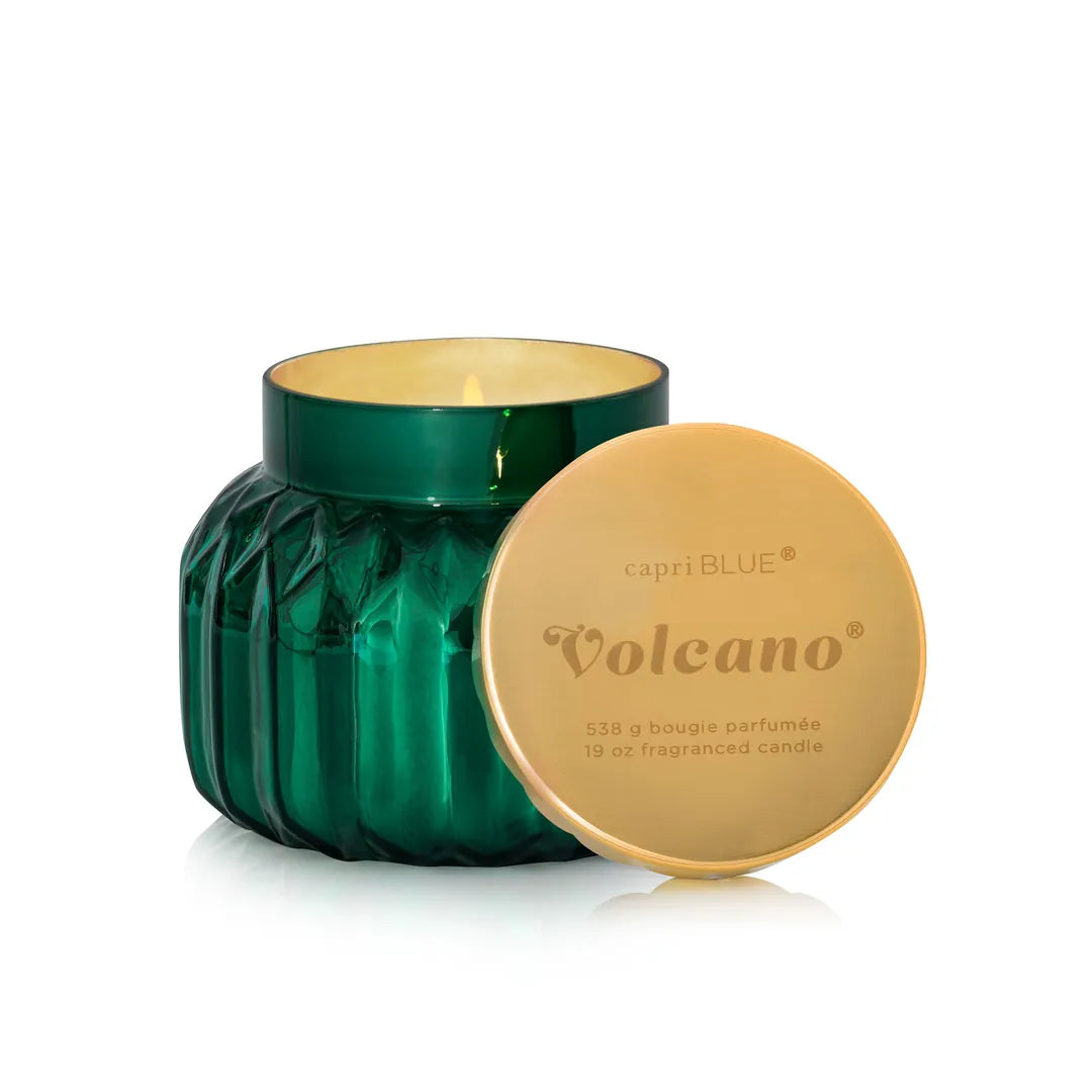 Green candle with a gold lid labeled 'Volcano' by capri BLUE on a white background