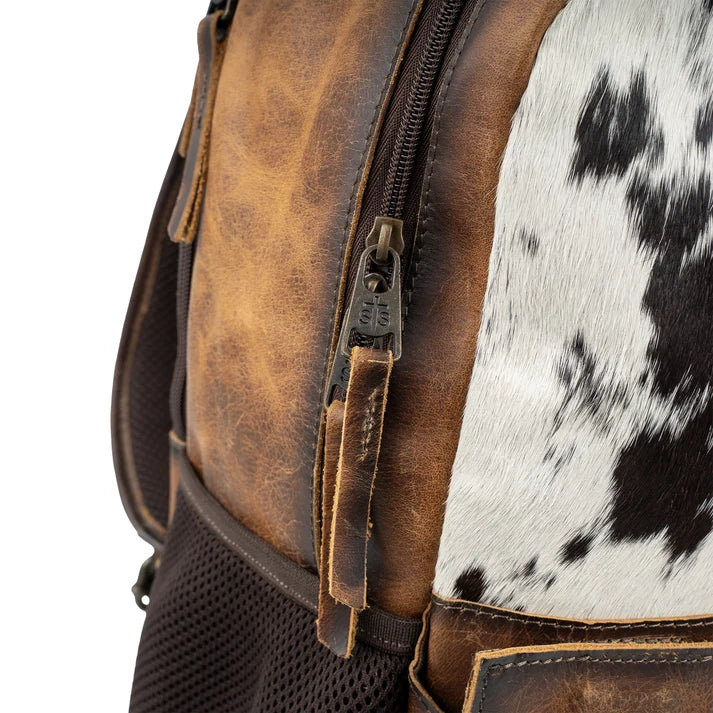 Close-up of a leather backpack with cowhide pattern on a white background