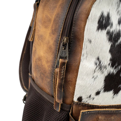 Close-up of a leather backpack with cowhide pattern on a white background