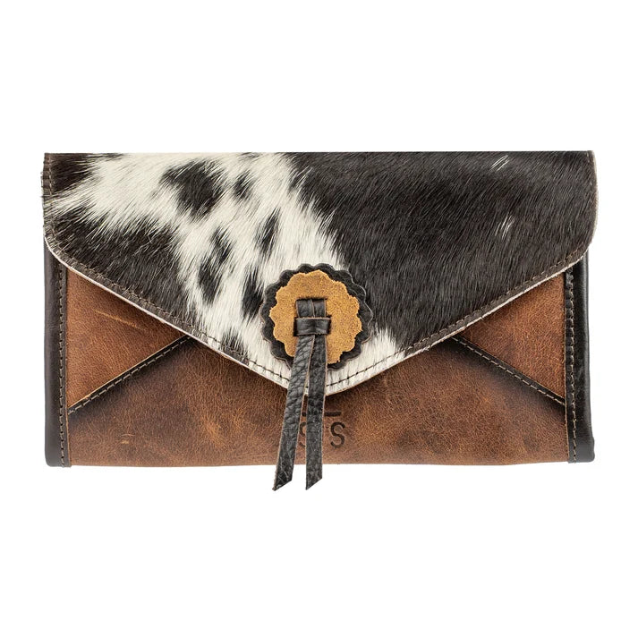 A western-style envelope clutch bag made of brown leather and black-and-white cowhide, featuring a scalloped gold-tone metal clasp and a black leather tassel.