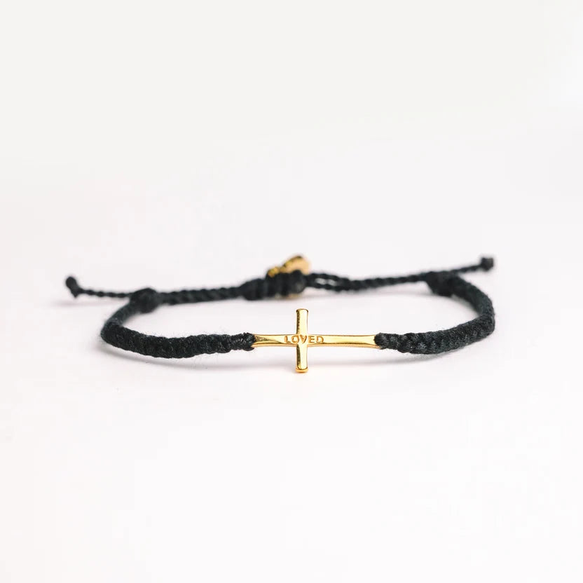 A black braided cord bracelet with a small gold cross charm engraved with the word 'LOVE', displayed on a clean white background.